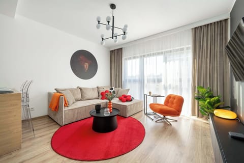 Bright studio interior with a modern corner sofa, red rug, and contemporary décor in warm tones.