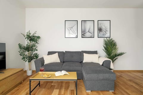 Bright living room with corner sofa, dining table and large windows filling the space with daylight.