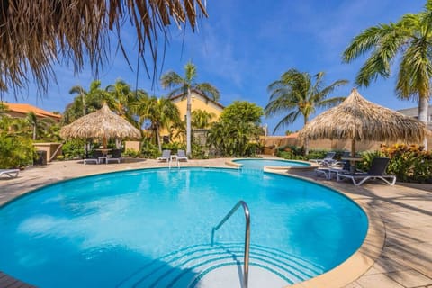 A refreshing tropical pool surrounded by palm trees and shaded loungers—an inviting spot to cool off, relax, and soak up the island sunshine.