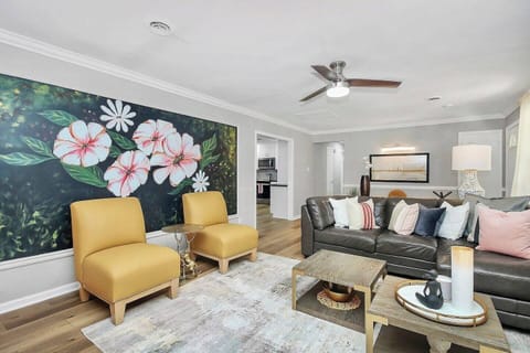 Relax in this bright, stylish living space featuring a hand-painted floral mural, cozy seating for ALL and thoughtful details that invite you to unwind, connect and feel at home during your stay.