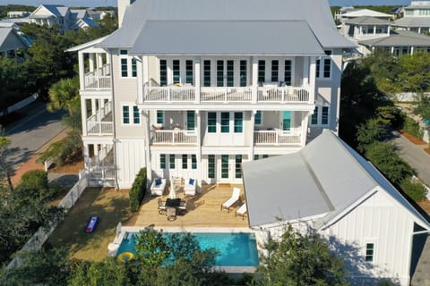 Stunning beachside property featuring multiple balconies, private pool, and spacious outdoor deck surrounded by coastal neighborhood charm.