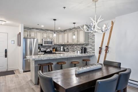 Beautifully renovated kitchen with stainless steel appliances, custom cabinetry, and a spacious island with bar seating. Opens to an elegant dining table ideal for meals and entertaining.