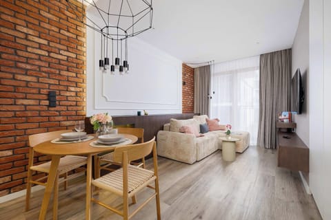 Exposed brick and soft lighting create a cozy atmosphere where the living and dining areas blend seamlessly, perfect for relaxing together.
