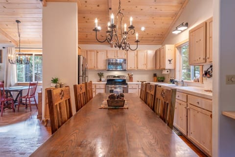 Gather around this beautiful rustic kitchen where warm wood tones and charming chandeliers create the perfect atmosphere for your mountain getaway meals and morning coffee conversations.