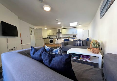 Open plan lounge with two sofas, leading to the dining and kitchen areas.
