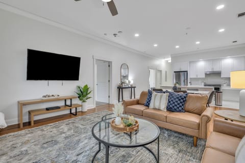 Bright living room featuring modern seating, a smart TV, and a ceiling fan.