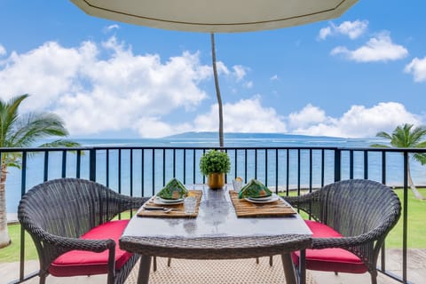 Private oceanfront balcony with a two-seat dining set, perfect for enjoying meals or drinks while overlooking the turquoise waters and swaying palms.
