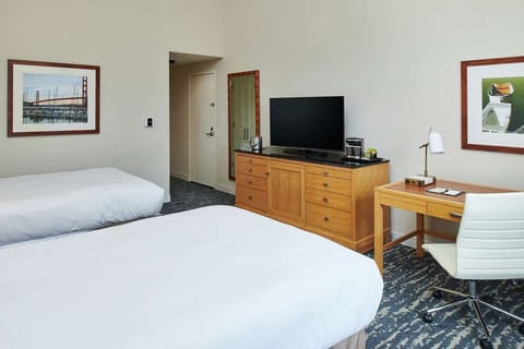 Room with two beds, dresser, TV, and small work desk