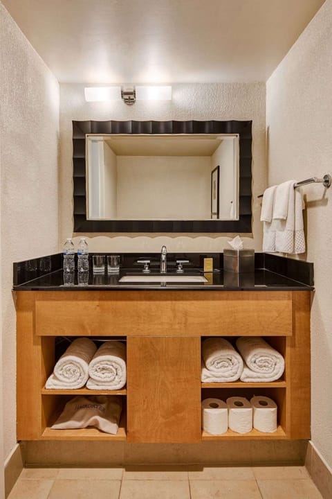 Bathroom sink with large mirror, rolled towels, and supplies