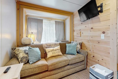 Sunny living area with wall-mounted TV and comfy couch. Perfect for relaxing after hiking or exploring.