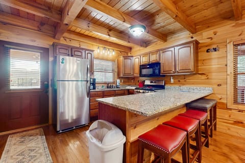 Fully equipped cabin kitchen with granite countertops, stainless appliances, and breakfast bar seating. Perfect for family meals, weekend getaways, and Smoky Mountain vacations near Gatlinburg & Pigeon Forge.