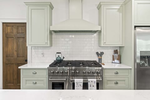 Professional-style gas range with custom vent hood and quartz countertops. Well-equipped kitchen perfect for cooking for large groups and vacation meals.