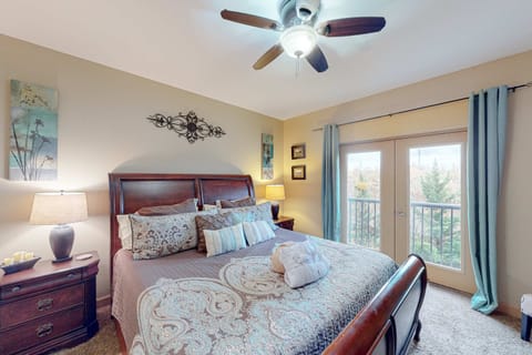 Spacious king bedroom with plush bedding, ceiling fan, and private balcony access. Relaxing retreat for couples and extended stays.
