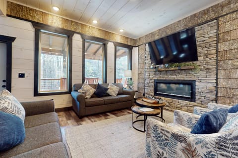 Inviting space with large windows, a stone fireplace, and charming decor awaits you!