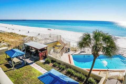 The stunning vista from the balcony presents a serene stretch of white sand beach, where the tranquil turquoise waters gently kiss the shore under a clear blue sky, inviting guests to indulge in sun-soaked relaxation.