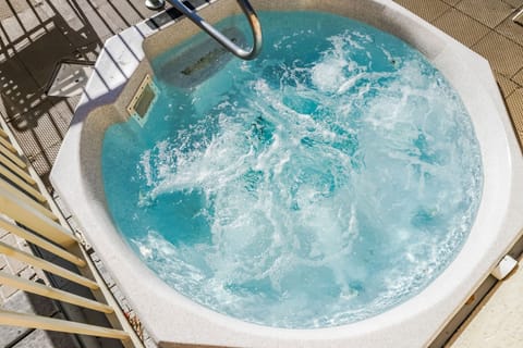 The outdoor hot tub bubbles invitingly, set against a backdrop of sun-drenched tile, offering a relaxing retreat for guests seeking a soothing escape after a day of fun in the sun.