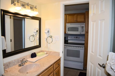 Another bathroom perspective captures a stylish vanity with a large mirror and ample organizational space, seamlessly melding practicality and comfort for guests during their beach getaway.