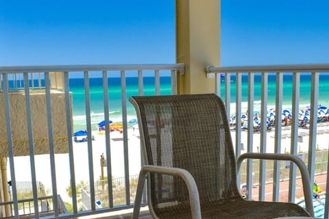 A relaxing balcony view overlooking the beach, complete with colorful umbrellas and the vibrant ocean waters beyond.