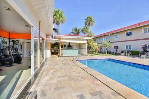 Unwind poolside under blue skies beside the airy gym.