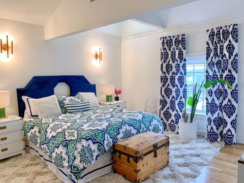 Master bedroom featuring a king size adjustable bed (remote for head/foot height), 55" flat screen mounted smart TV, en suite full bath with jacuzzi tub and balcony with seating. There is a closet and large dresser in the room, as well.