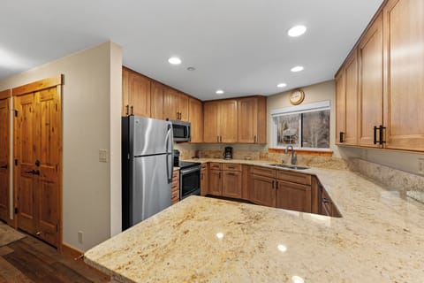 Full kitchen featuring stainless steel appliances and breakfast bar seating two.