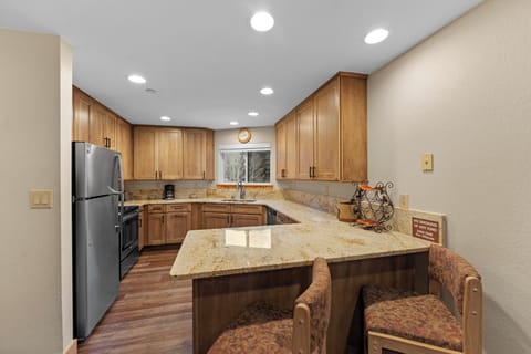 Full kitchen featuring stainless steel appliances and breakfast bar seating two.