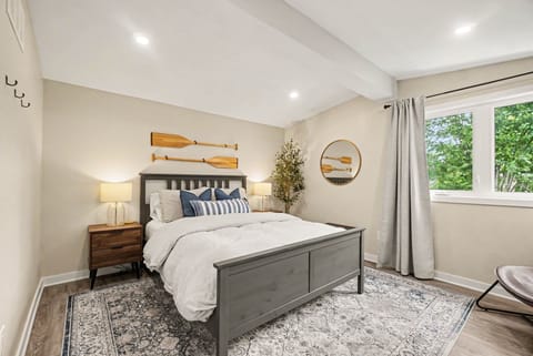 Bright, cozy primary bedroom featuring a plush queen-size bed, modern neutral decor, and plenty of n