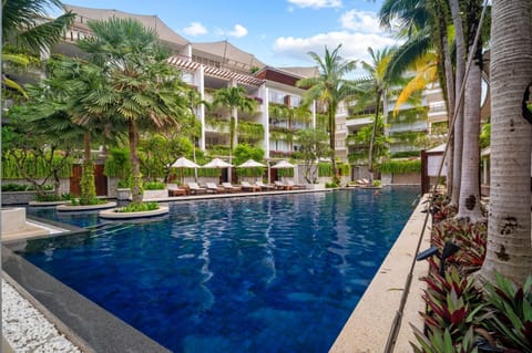 Serene swimming pool surrounded by palm trees and tropical landscaping.