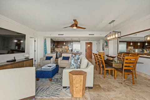 Open-concept living area with plush seating, and a view into the kitchen, complemented by neutral tones and ceiling fans.