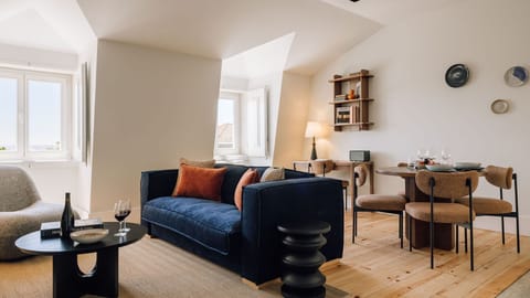 Chic living space with navy sofa, cozy armchair, wooden floors, natural light, modern dining area, and elegant decor. 
#AndoLiving
#ModernLiving 
#CozyHome 
#InteriorDesign