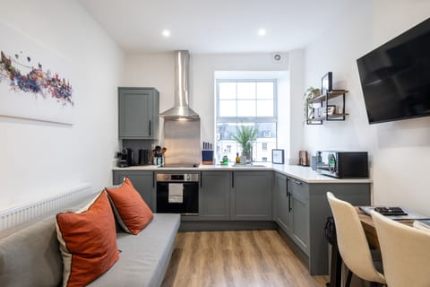 Open-plan kitchen and living area with a cosy sofa and smart TV for relaxing stays.