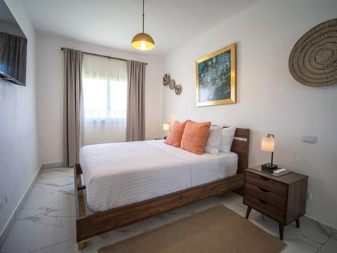 Bright bedroom featuring artful decor, plush pillows, and natural light.