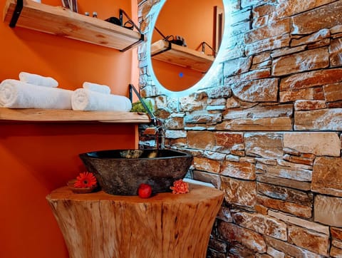 Vasque pierre et miroir lumineux – salle de bain romantique