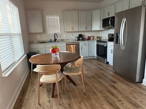 Enjoy a dining table set within a bright, open-concept kitchen—perfect for sharing meals in a clean and inviting space.
