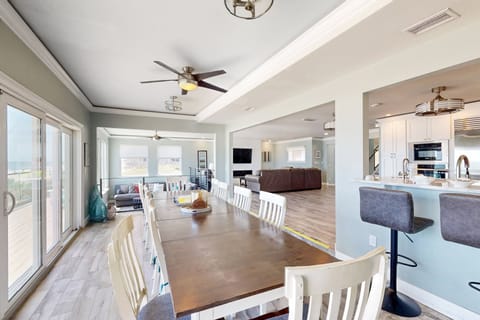 Expansive open-concept dining area flowing into the kitchen and living room, filled with natural light. Perfect for gathering, relaxing, and enjoying a seamless beach stay with family and friends.