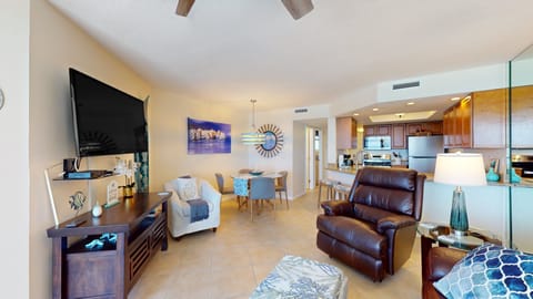 Bright coastal living area with comfy seating, beachy décor, and an open layout leading to the kitchen—perfect for relaxing after a fun-filled beach stay.