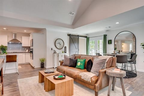 Bright and airy open-concept living space featuring a stylish leather sofa, modern decor, and a cozy dining area on the side.