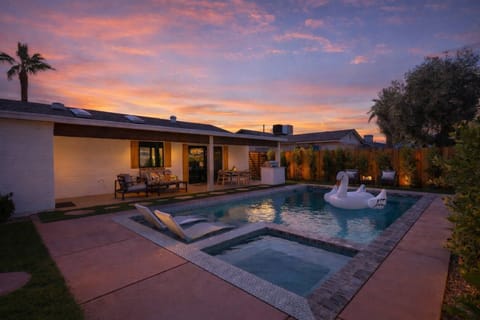 Private backyard featuring a sparkling pool and spa, sun loungers, and a covered patio with outdoor seating, dining area, bathroom, and a BBQ grill.