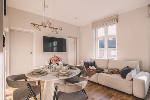 Bright living room with dining area and TV – perfect to unwind after exploring Poznań’s center.