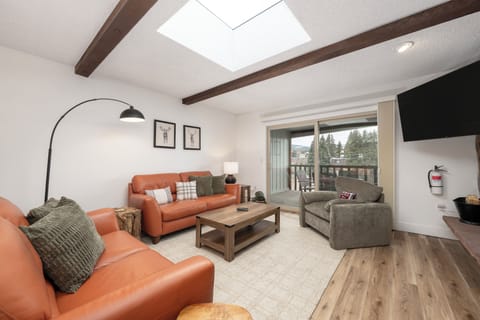 Unwind in this stylish living room featuring exposed beams, a cozy fireplace, and natural light from the skylight above.