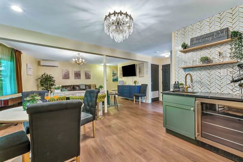 This beautifully designed wet bar features sage green cabinetry, a sleek wine fridge, gold fixtures, and open shelving with stylish accents—an inviting space to pour a drink, gather with friends, and enjoy the good times.