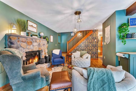 Main Floor Living Room: Gather around the stunning stone fireplace in this cozy yet stylish space that connects effortlessly to the kitchen and dining area—complete with bold wallpaper and thoughtfully curated design.