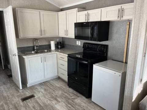 A clean, modern kitchen designed for simple, stress-free cooking. It features a drip coffee maker, full stove/oven, and fridge, with plenty of cabinet space and a sleek, uncluttered layout—perfect for easy meals, morning coffee, and relaxed stays.