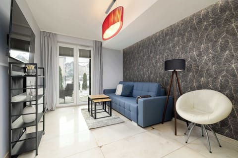 A bright living area featuring a blue sofa, patterned accent wall, and modern décor with a floor lamp and coffee table.