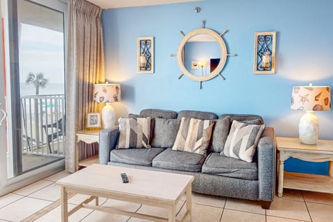 Bright beach stay living area with coastal décor, plush seating, and sliding doors to an ocean-view balcony. Relax after a day at the beach in this inviting seaside retreat, perfect for your coastal vacation getaway.
