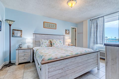 Recharge in this bright, beach-themed bedroom featuring a comfortable bed, coastal décor, and natural light—an inviting retreat designed for restful nights during your perfect beach stay.