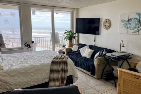 Bright oceanfront studio featuring a cozy bed, sleeper sofa, and panoramic beach views. Enjoy waves from your window, easy beach access, and a relaxing coastal stay perfect for your seaside getaway.