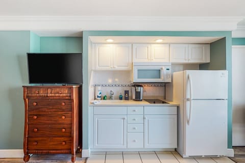 Convenient beach stay kitchenette with fridge, microwave, cooktop, and coffee maker, paired with a flat-screen TV and storage. Perfect for easy meals and relaxing downtime during your coastal vacation.