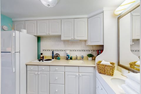 Cozy beach stay kitchenette with white cabinetry, cooktop, and ample counter space—perfect for easy seaside meals. A clean, bright layout keeps your ocean getaway comfortable and convenient.