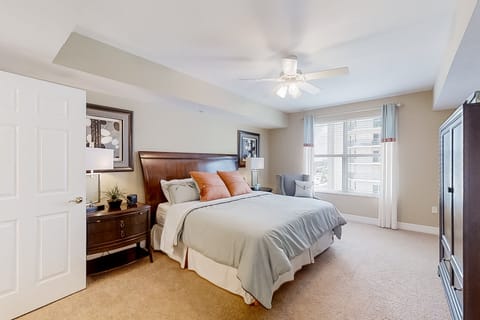 Relax in this bright master bedroom featuring a plush king bed, soft beach-inspired décor, and plenty of natural light—perfect for unwinding after a sun-soaked beach stay.
